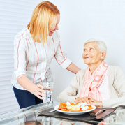 caregiver serving a meal to a senior woman